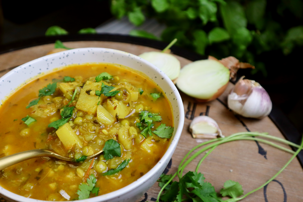 Instant Pot Aloo Matar Recipe (Potato & Peas Curry) being  eaten with a spoon